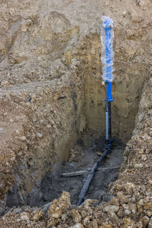 Installation of new blue fire hydrant at construction site. Hole in the ground with fire hydrant installation.の写真素材