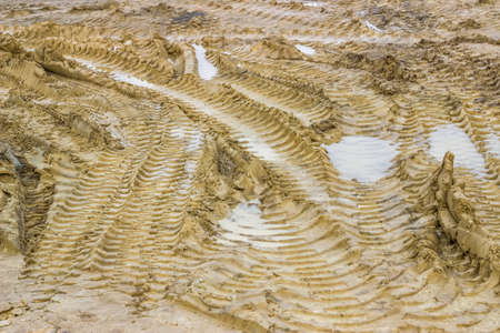 Muddy road with tire tracks and puddles 2. Selective focus.