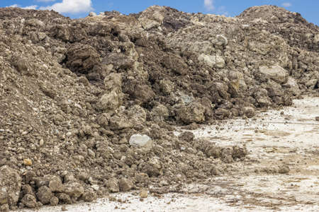 Construction dirt pile under blue sky and cloudsの写真素材