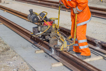 Close up of tramway track construction worker with rail grinding machine, grinding rail machine....