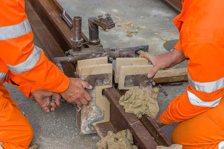 Worker installing mould and using mould material on tram rail before thermit welding process.の写真素材