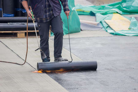 Builder worker at floor slab insulation work, tar barrier over concrete slabs to keep water outの写真素材