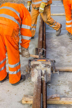 Tracks being laid, builders weld and joining segments of the rail.
