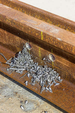 Holes in the rail for the bolts with metal swarfs. Selective focus.の写真素材