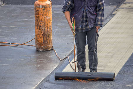 Builder worker at floor slab insulation work, insulation tar material over concrete slabs to keep water out.の写真素材