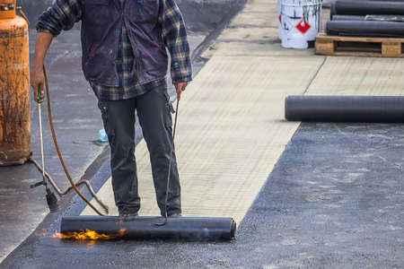 Builder worker at floor slab insulation work, insulation tar material over concrete slabs to keep water out.の写真素材