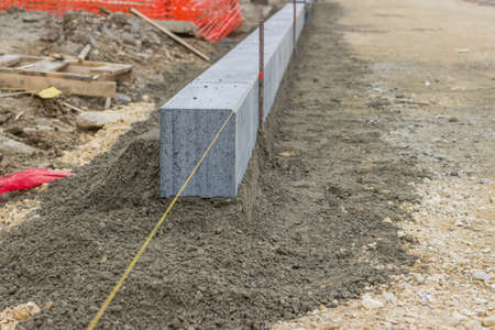 Large grey granite curb stone and string with stakes to level at road construction site. Selective focus.の写真素材