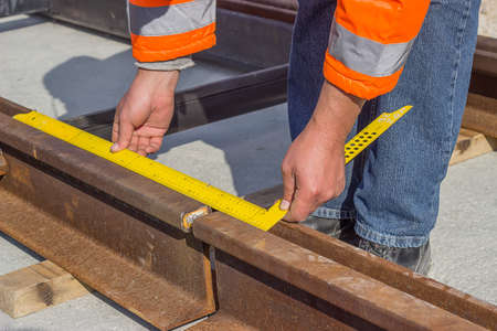 Preparation for rail welding process. Tramway track worker worker measures rail gap in the street.の写真素材