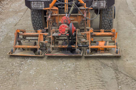 Truck mounted plate compactor compacting gravel at road construction site. Selective focus.