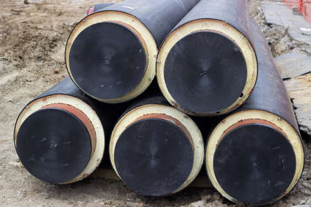 Stack of underground insulated pipes for heat system  at construction site. Selective focus.の写真素材