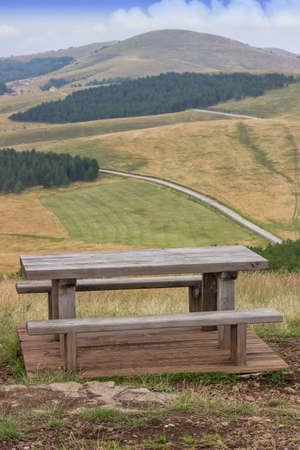 Wooden seating bench with table in nature, makes a good resting place.の写真素材