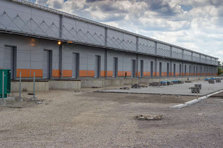 New modern and large warehouse building with warehouse gates, under construction. For semi truck trailer loading and unloading.の写真素材