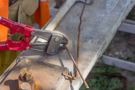 Cutting rebar with bolt cutters. Using Bolt Cutters to cut. Selective focus and motion blur.の写真素材
