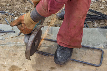 Builder worker cutting spacer for the rebar in a concrete post,  using angle grinder to grinding.の写真素材