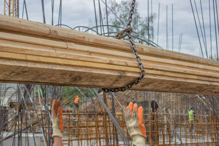 Lifting timber plank for formwork installation at construction site. Selective focus and motion blur.の写真素材
