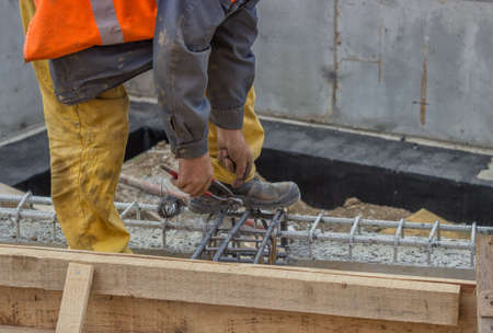 Builder worker tying a spacer to a rebar at construction site.  Selective focus.の写真素材