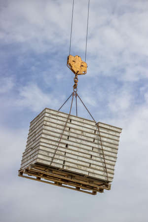 lifting pallet with formwork elements by crane at the building siteの写真素材
