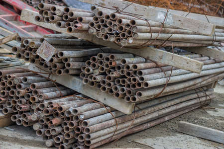 Pile of rusty scaffold tubes at the building site. Selective focus.