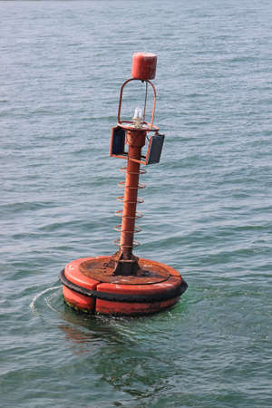 Red navigation buoy with solar panels floating on the sea.