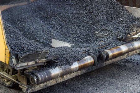 Hot asphalt in paver machine. Paver machine full of fresh asphalt. Made with selective focus and and shallow dof.の写真素材