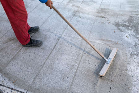 Install polymeric sand by brooming it into the paver joints during construction works. Some motion blur present.の写真素材