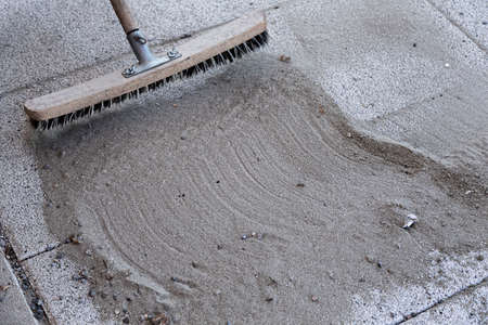 Install polymeric sand by brooming it into the paver joints during construction worksの写真素材