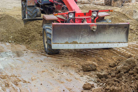 Motor grader working on leveling gravel at road construction site. Made with selective focus and and...