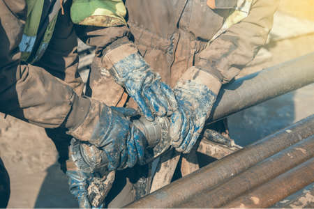 Worker hands checks a diamond core drill bit. Made with shallow dof and vintage style.