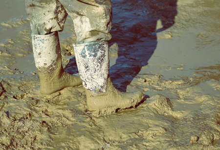 Muddy work boots, human leg with dirty rubber boots. Made with shallow dof and vintage style.の写真素材