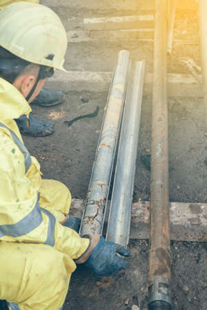 Technician holds a core sample, just drilled rock and sediment samples that is later analyzed. Made with selective focus and and shallow dof. Vintage style.の写真素材