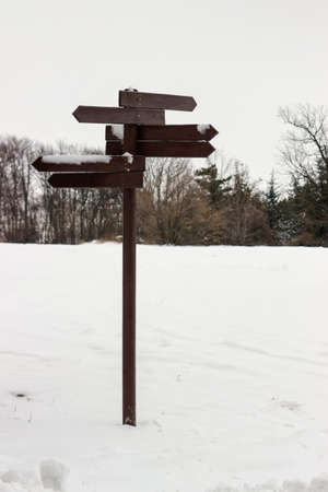 Wooden direction sign covered with snow and blank spaces for textの写真素材