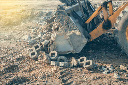 Front loader with mounted wide bucket loading concrete waste for recycling at building site.  Selective focus and vintage style.の写真素材