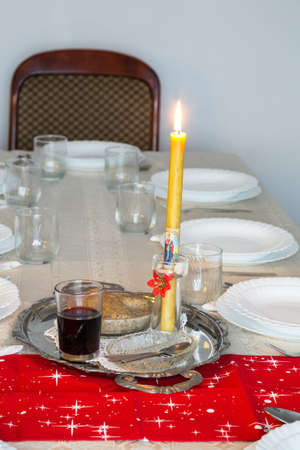 Holiday table with candle, cup of wine and sweet wheat in a bowl. Selective focus.の写真素材