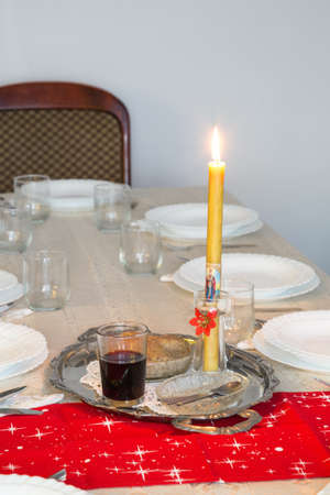 Holiday table with candle, cup of wine and sweet wheat in a bowl. Selective focus.の写真素材