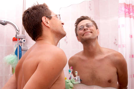 The man examines the reflection in a mirrorの写真素材