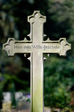 old stone cross with the writing; lord thy will be done, on a grave in a cemeteryのeditorial素材