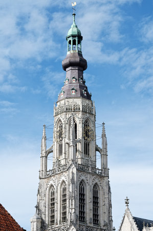 The gothic church tower of the protestant Onze-Lieve-Vrouwekerk in Breda against a blue sky with cloudsの写真素材