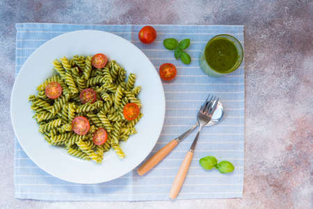 Italian pasta fusilli with green sauce Basil pesto, parsley and nuts in a plate on a concrete table. traditional Italian dish.の写真素材