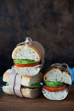 Vegetable vegetarian sandwiches with avocado and tomatoes on a wooden background for lunch.