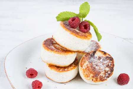 mini cheesecakes of cottage cheese decorated with fresh berries on a white plate