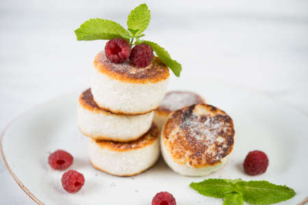 mini cheesecakes of cottage cheese decorated with fresh berries on a white plate
