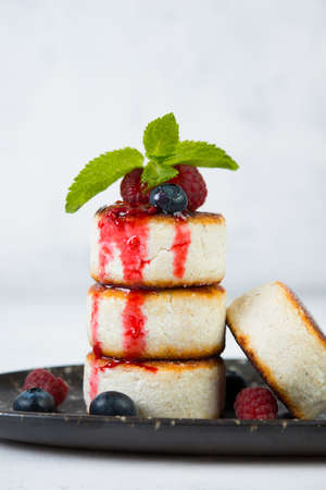 Small cheesecakes with berry sauce on a white background. Wholesome breakfastの写真素材