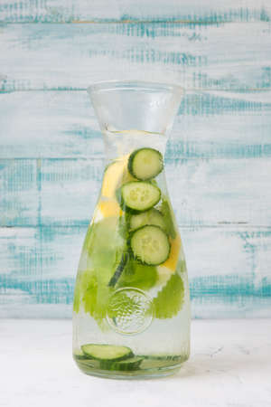 Homemade natural detox water with cucumbers, lemon and mint on wooden backgroundの写真素材