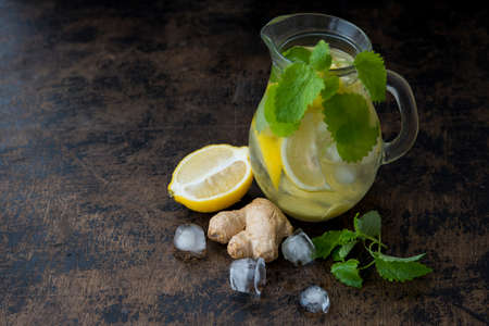 Healthy homemade detox drink with lemon, mint and ginger. Homemade lemonade in a jug on a dark background.の写真素材
