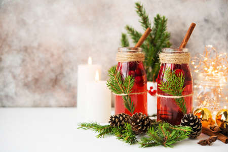 Two bottles of traditional festive mulled wine with berries and spices on a white table with Christmas garlands and Christmas decorationsの写真素材