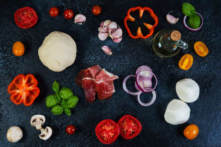 The ingredients of a pizza lay  on a black concrete background. Top view. Horizontal orientation.の写真素材