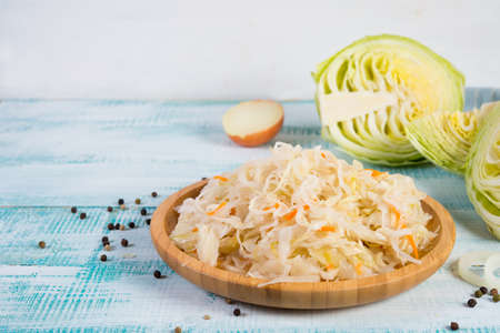White fermented cabbage lies in a wooden plate on the right of the frame. Horizontal orientation with copy space.の写真素材