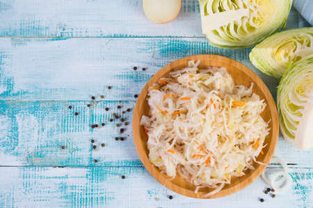 White fermented cabbage lies in a wooden plate on the right of the frame. Top view with copy space.の写真素材