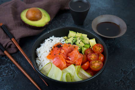 A popular Hawaiian dish, Poke in a plate of red fish, rice and vegetables. Poke plate on a black...