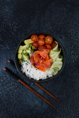 A popular Hawaiian dish, Poke in a plate of red fish, rice and vegetables.  Top view.